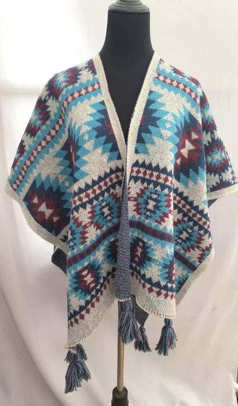 Open-front knitted wrap poncho with Aztec geometric pattern in teal, burgundy, navy, and cream with tassel fringe hem on mannequin - free sample within 7 days