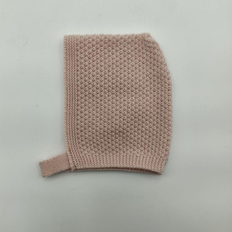 Flat lay of a soft blush pink knitted baby bonnet with seed stitch texture and ribbed chin strap on white background - 5-day digital sample ready