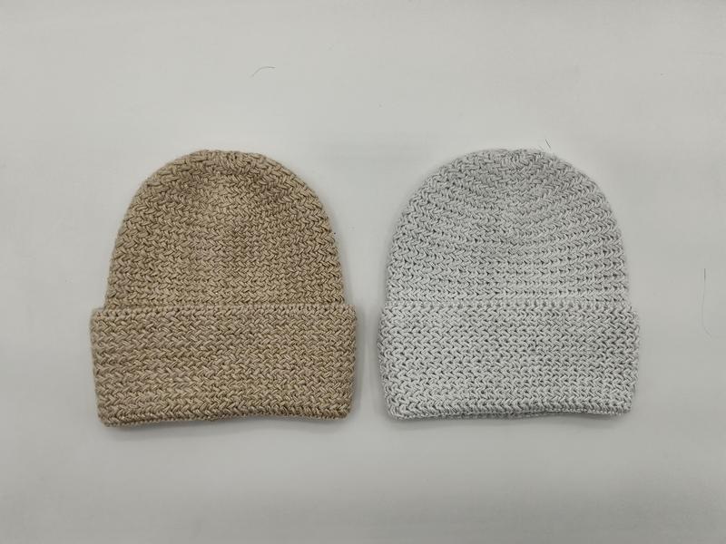 Two chunky knit cuffed beanie hats laid flat, one in beige and one in light grey, showing textured woven stitch pattern - wholesale price for Middle East buyers