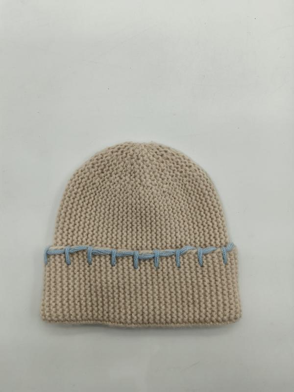Beige chunky knit cuffed beanie hat with decorative light blue whipstitch detail along the folded brim, laid flat on white background - EU REACH compliant material