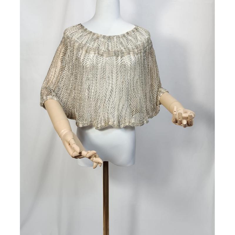 Beige and gold metallic open-knit crochet cropped poncho top displayed on a white mannequin with wooden articulated hands - wholesale price for USA buyers