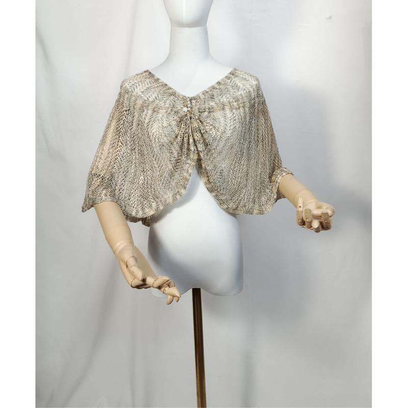 Beige and gold open-knit lace capelet shawl with tie front closure displayed on white mannequin with wooden arms - wholesale price for Middle East buyers