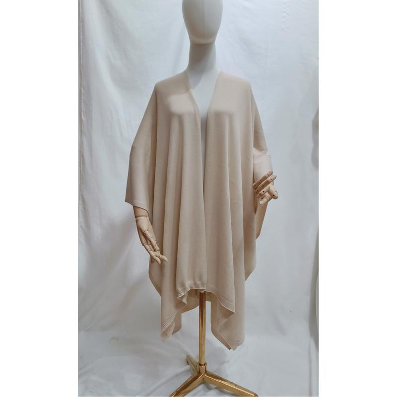 Beige oversized open-front knit wrap poncho cape draped on a mannequin, soft neutral tone with ribbed hem detail - request quote reply same day
