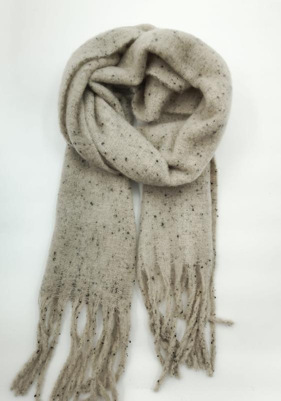 Beige speckled knit scarf loosely coiled with fringe ends on white background, featuring dark fleck pattern - private label service available
