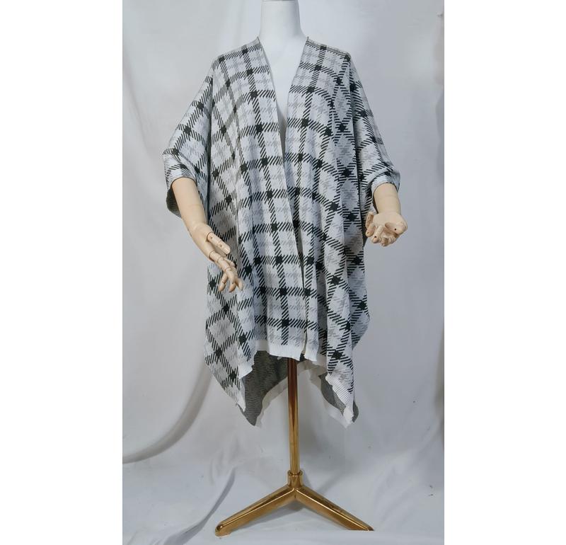 Mannequin wearing a black and white plaid knit open-front poncho wrap cape with draped asymmetric hem on gold stand - winter accessories wholesaler