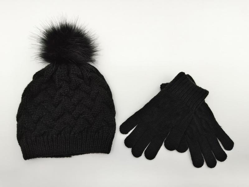 Black cable knit winter beanie hat with faux fur pom-pom and matching knit gloves set on white background - ask bulk pricing get discount