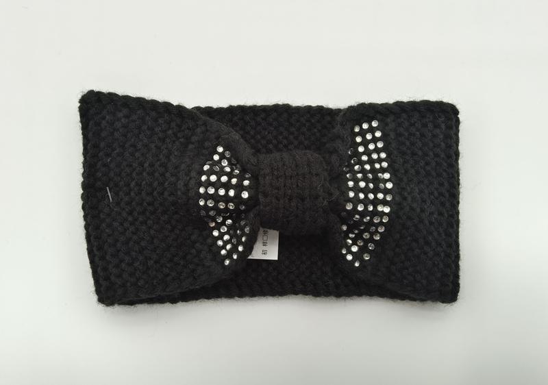 Black chunky knit winter headband with decorative rhinestone-studded bow detail, laid flat on white background - express production 15 days