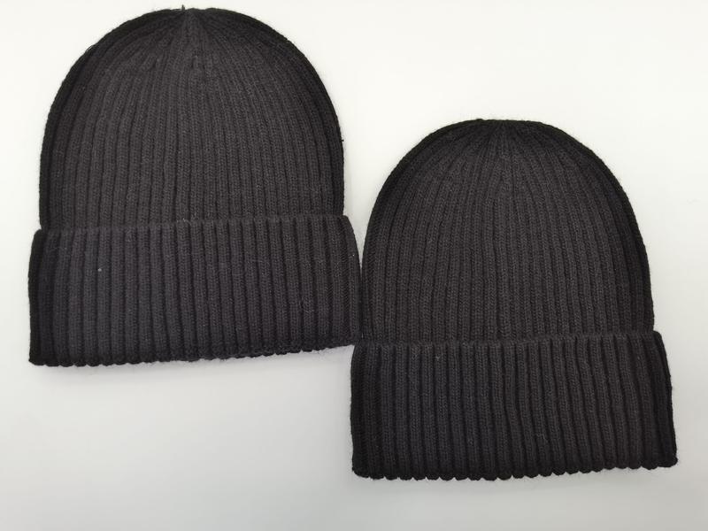 Two black ribbed knit cuffed beanie hats laid flat on white background, one larger and one smaller - wholesale price for Middle East buyers