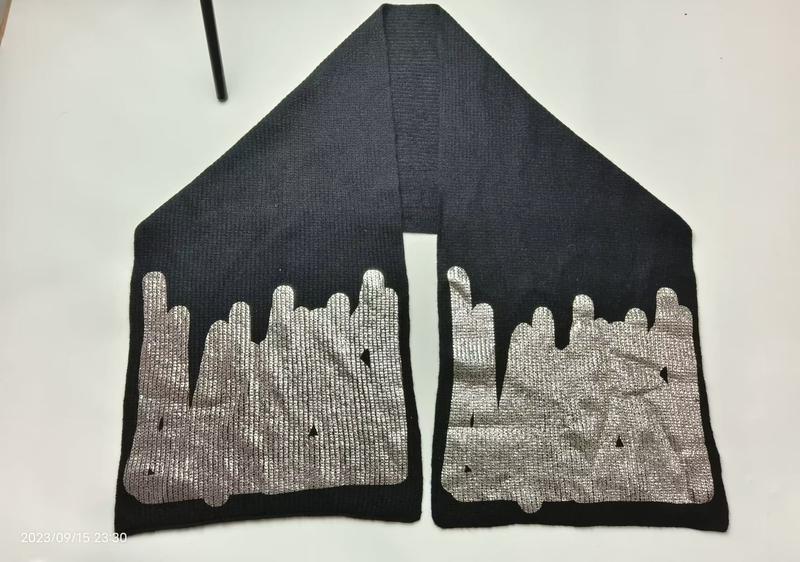 Black ribbed knit scarf laid flat showing both ends with large metallic silver drip or melt pattern print on dark fabric - certified scarf manufacturer China - contact for custom design quote