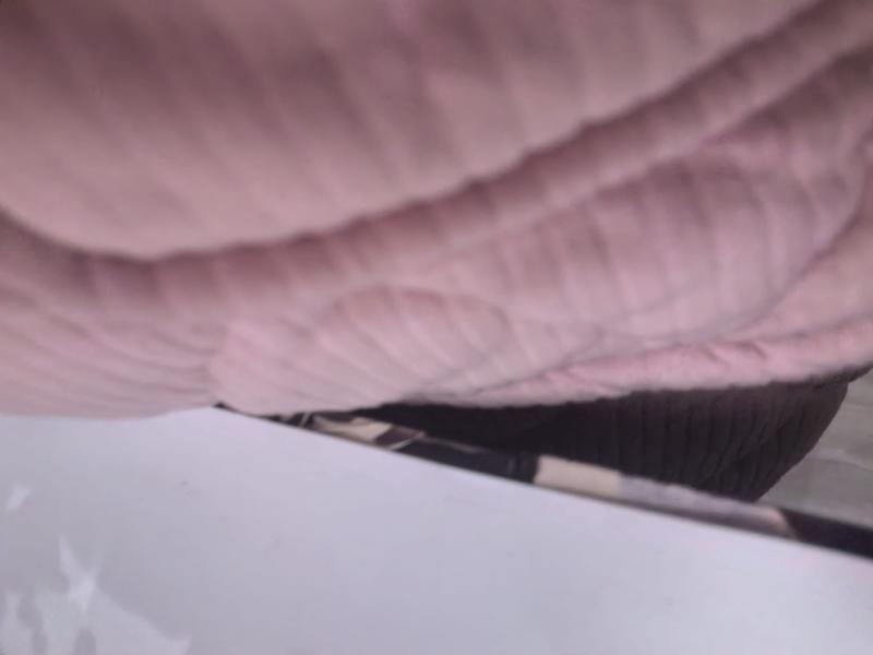 Close-up of a soft blush pink quilted throw blanket with raised waffle weave texture draped over a surface - free sample within 7 days