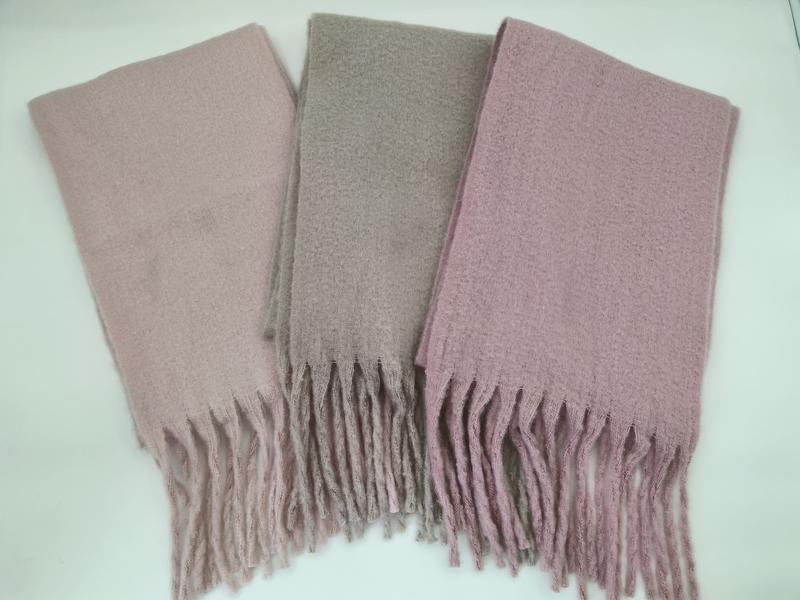 Three folded boucle scarves with fringe ends in blush pink, taupe, and mauve laid flat on white surface - event merchandise supplier