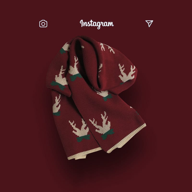Burgundy knitted scarf with repeating reindeer pattern in cream and green, folded on dark red background - private label service available