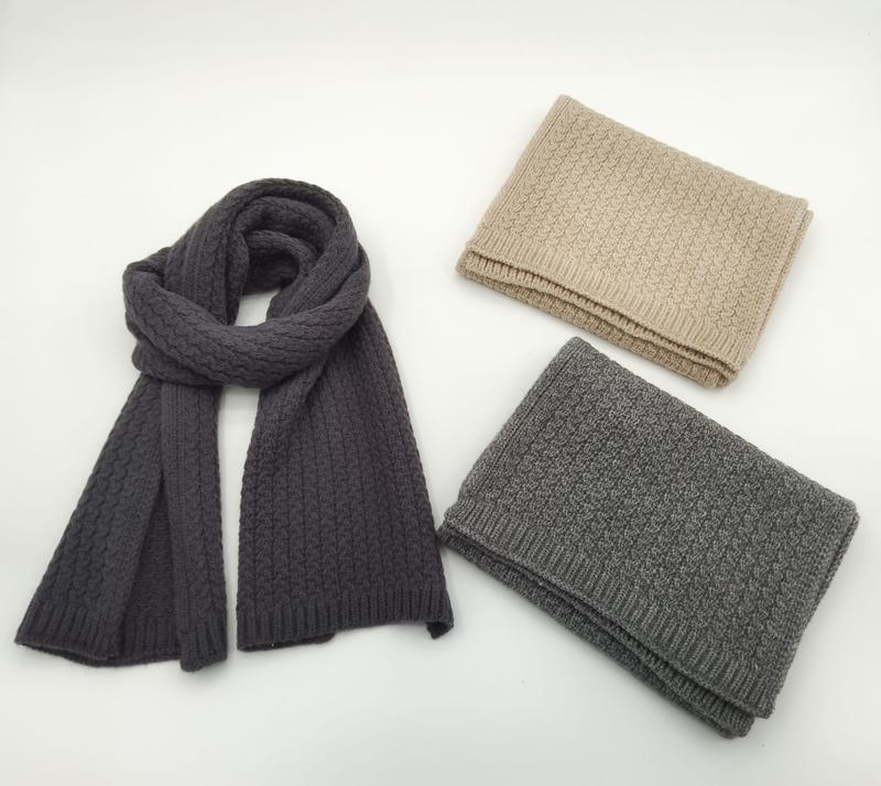 Three cable knit scarves in charcoal, light gray, and beige – one draped open, two folded, on white background - certified scarf manufacturer China - gift shop wholesale supplier