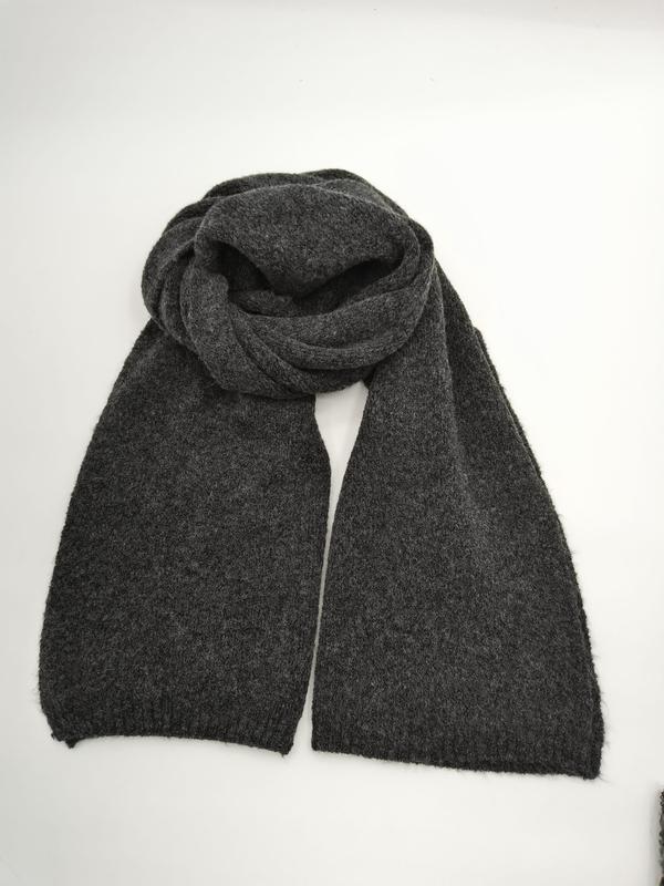 Dark charcoal grey knitted scarf loosely coiled and laid flat on white background showing two long ends - corporate gift customization