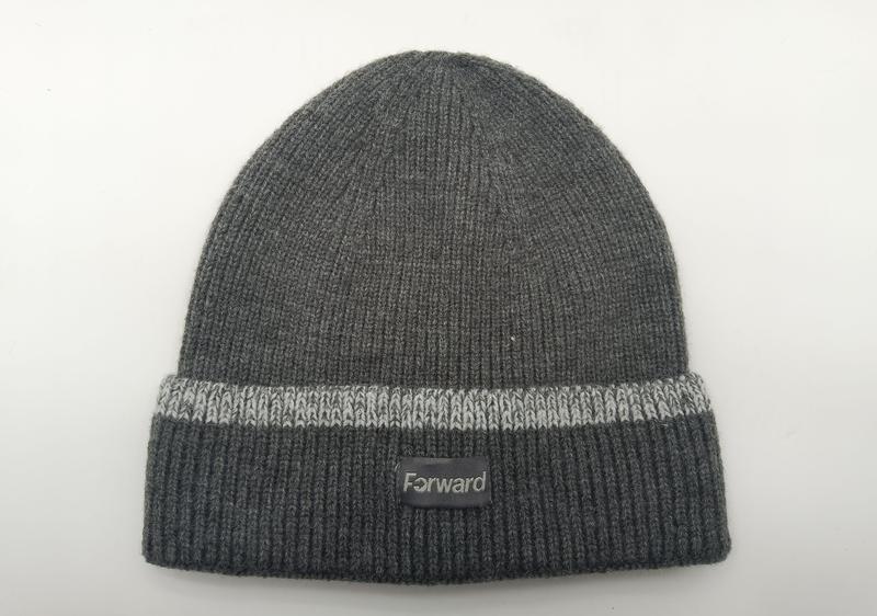 Charcoal grey ribbed knit beanie hat with light grey stripe on folded cuff and small label patch, laid flat on white background - wholesale price for USA buyers