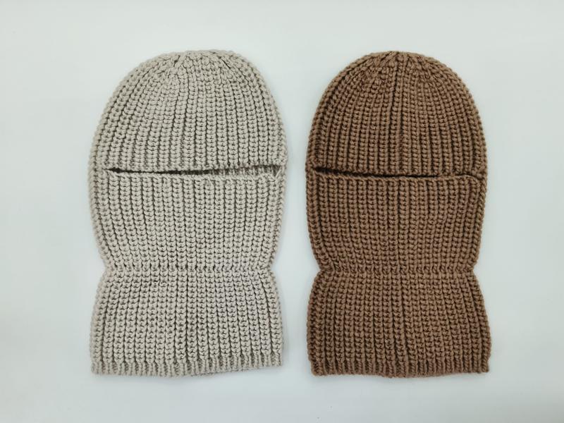 Two chunky knit balaclava ski masks laid flat, one in light beige and one in warm brown, showing eye slit opening and ribbed texture - BSCI + Oeko-Tex + GRS certified