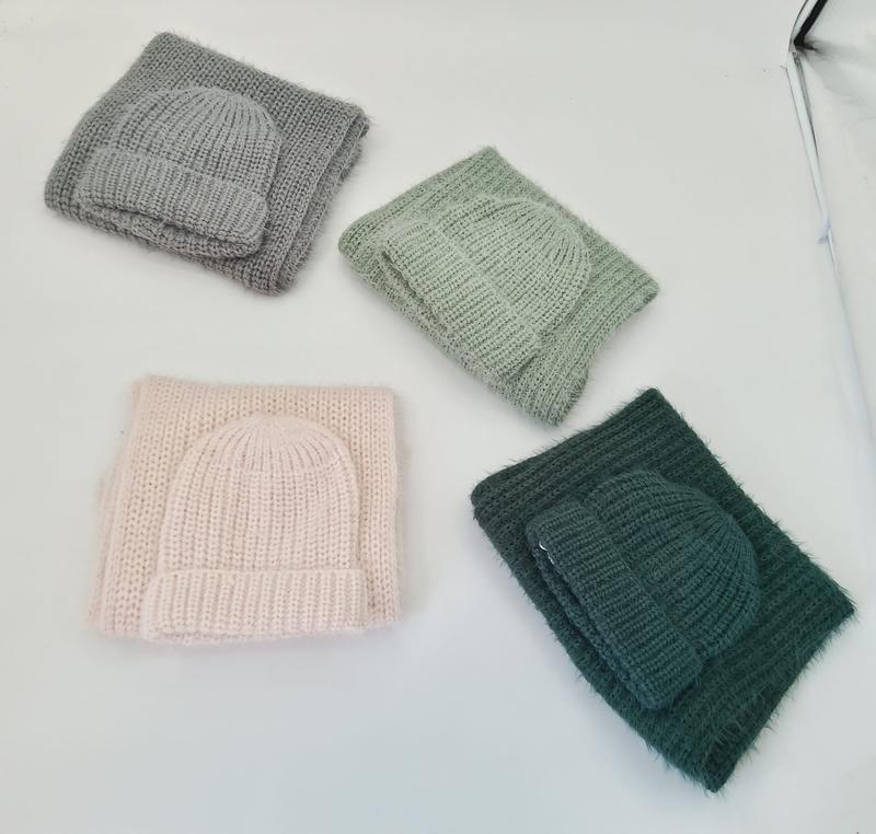 Four folded chunky knit winter hat and scarf sets in gray, sage green, blush pink, and dark forest green on white background - boutique retail bulk order