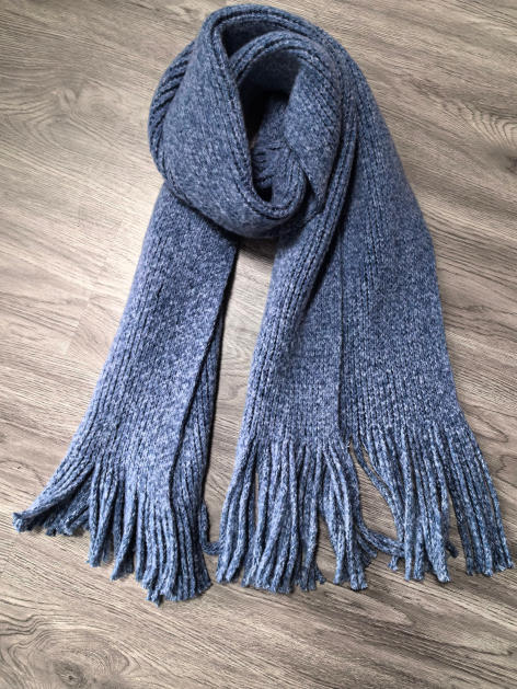 Long chunky knit grey marl winter scarf with tassel fringe ends, folded on wooden floor - gift shop wholesale supplier