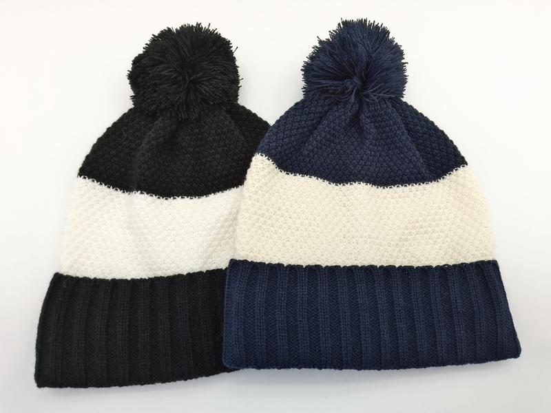 Two color block knit beanies with pom-poms in black-white and navy-white stripe patterns laid flat on white background - air shipping 5-7 days arrival