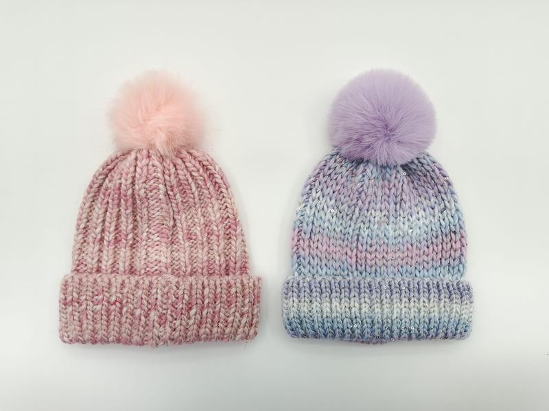 Two chunky knit pom-pom beanies side by side: pink marl and lavender blue tie-dye with faux fur pom-poms on white background - custom size no extra charge