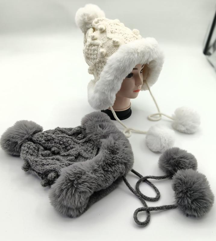 White and gray chunky knit trapper hats with faux fur lining, ear flaps, and pom pom ties displayed on mannequin head - email us get price list now