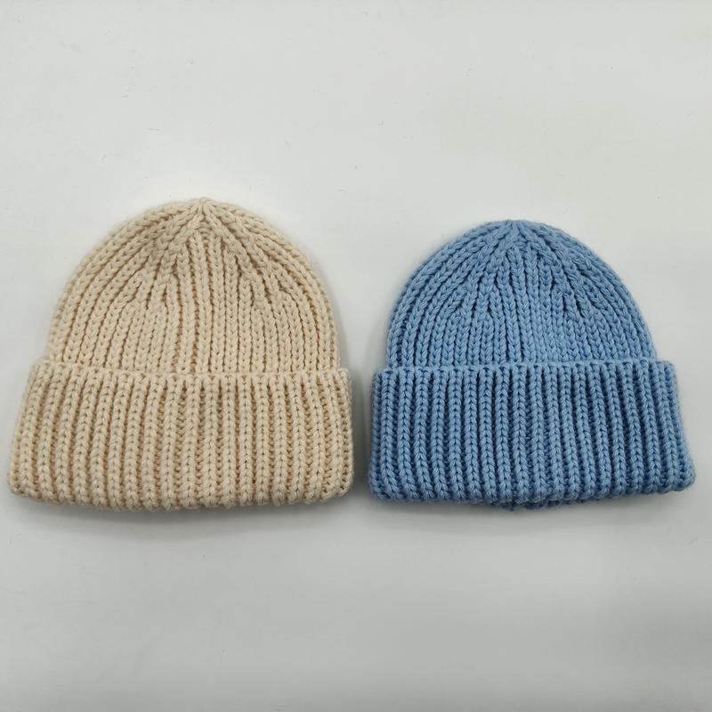 Two chunky ribbed knit beanies laid flat, one in cream and one in sky blue, with folded cuff detail on white background - sample order 10pcs available