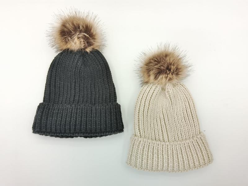Two chunky ribbed knit beanies with faux fur pom poms in charcoal gray and cream beige on white background - private label service available