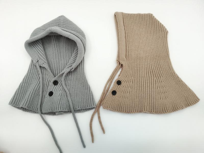 Two ribbed knit hooded neck warmers in gray and beige with black buttons and drawstring ties, laid flat on white background - custom Pantone color matching