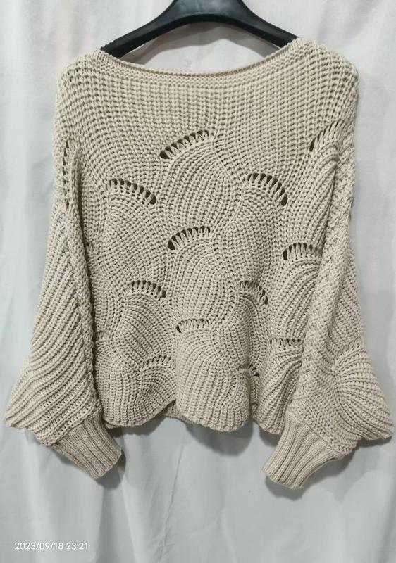 Cream beige oversized crochet knit pullover sweater with open fan stitch pattern and wide bell sleeves on hanger - EU REACH compliant material