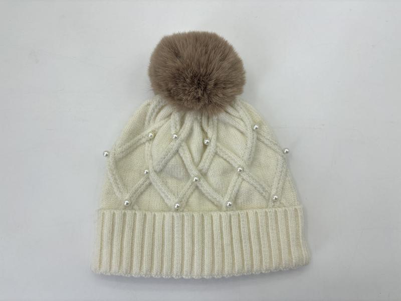Cream cable knit winter beanie with pearl bead accents, ribbed cuff, and large taupe faux fur pom-pom on top - WhatsApp quote in 2 hours