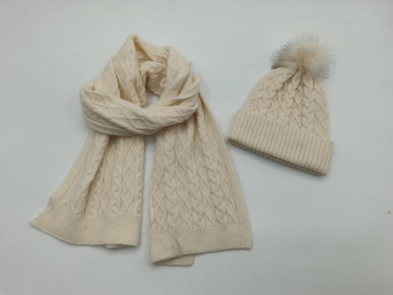 Cream cable knit winter scarf and matching beanie hat with faux fur pom-pom on white background - bulk order 20-day delivery