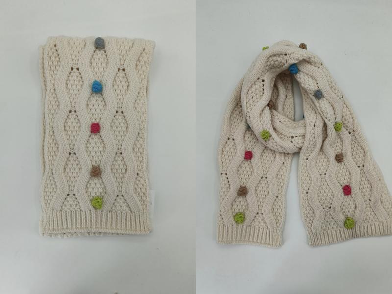 Cream cable knit scarf with colorful bobble details shown folded and draped, featuring blue, pink, green, and tan yarn knots - custom packaging design free