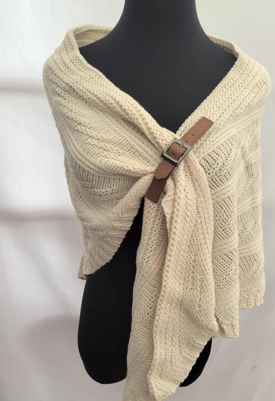 Cream chunky cable knit wrap shawl with brown leather buckle fastener displayed on black mannequin, cozy winter accessory - wholesale price for USA buyers