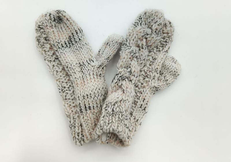 Pair of cream chunky knit mittens with black speckle detail and thumb, laid flat on white background - tiered pricing available ask quote