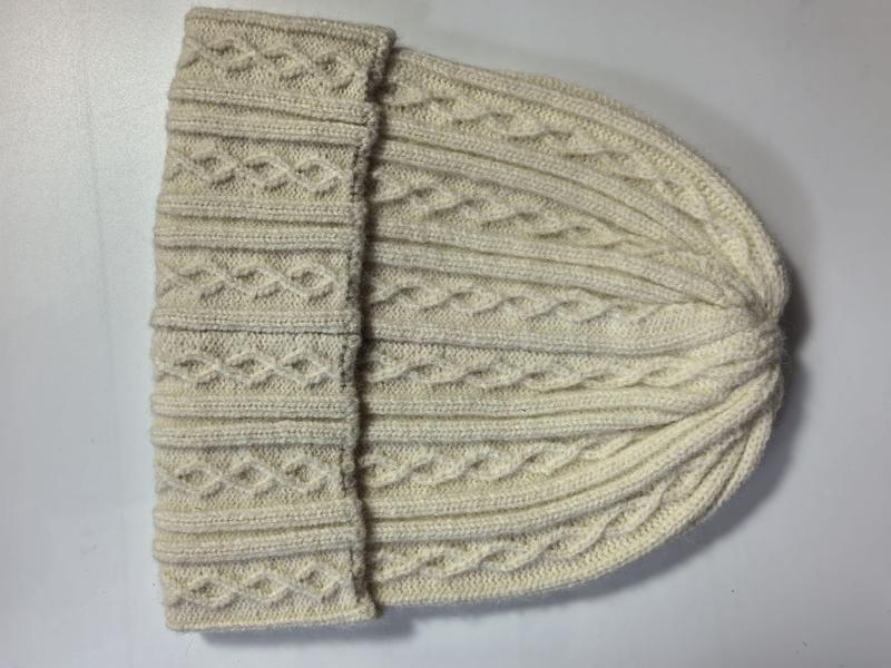 Cream ivory cable knit wool beanie hat laid flat showing folded cuff and textured diamond pattern stitching - wholesale price for Europe buyers