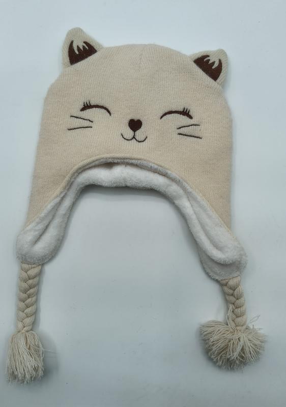Cream knitted cat face winter hat with ear flaps, braided ties, pom poms, fleece lining, and embroidered cat features - event merchandise supplier