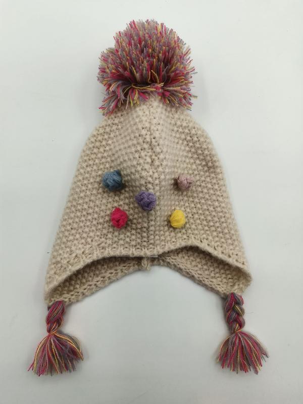 Cream knitted earflap hat with multicolor pompom on top, small colorful yarn bobbles, and braided tassels with fringe ends - Oeko-Tex Standard 100 certified