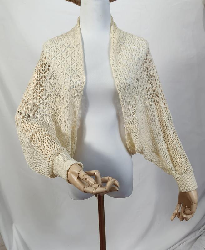 Cream ivory open-knit crochet bolero shrug with balloon bishop sleeves and ribbed cuffs on a mannequin - contact for custom design quote