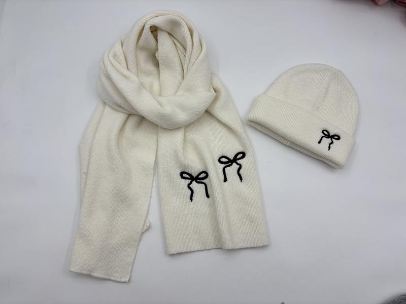 Cream ribbed knit winter hat and scarf set with black embroidered bow details laid flat on white surface - factory direct price no middleman