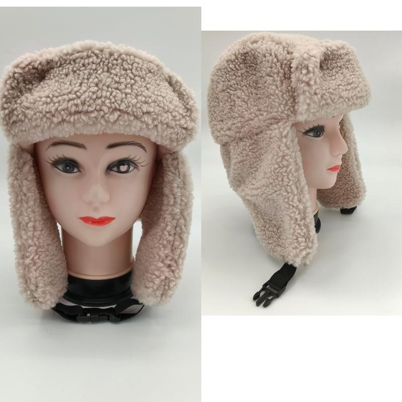 Cream sherpa fleece trapper ushanka hat with foldable ear flaps and adjustable chin strap shown on mannequin head, front and side view - hotel amenity scarf supplier