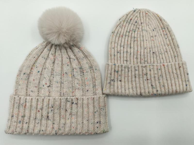 Two cream speckled knit winter beanies side by side, one cable-knit with faux fur pom-pom, one ribbed with folded cuff - retail buyer inquiry welcome - 5-day digital sample ready