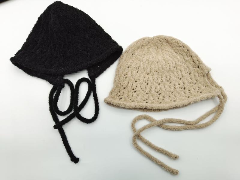 Two handmade crochet knit bucket hats with tie strings laid flat, one black and one beige, showing open lace pattern texture - EU REACH compliant material