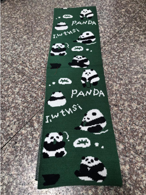 Dark green knitted scarf featuring repeating black and white panda bear illustrations with PANDA text, laid flat on tile floor - ISO 9001 quality controlled