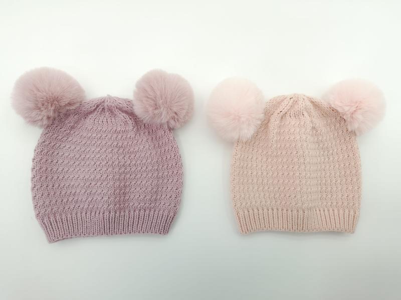 Two knitted winter beanies with double faux fur pom-poms, one in mauve purple and one in blush pink, on white background - private label service available