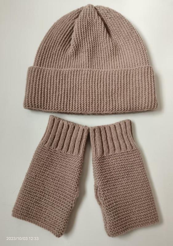 Handknit dusty pink ribbed beanie hat and matching fingerless mittens set laid flat on white background - winter accessories wholesaler