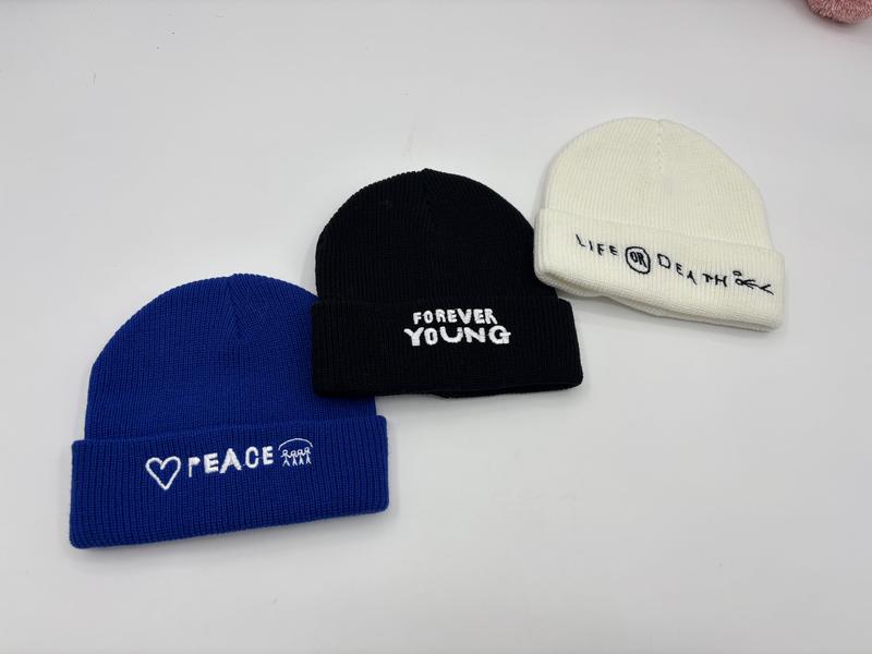 Three ribbed knit cuffed beanies in blue, black, and cream with embroidered slogans Peace, Forever Young, and Life or Death - certified scarf manufacturer China - ISO 9001 quality controlled