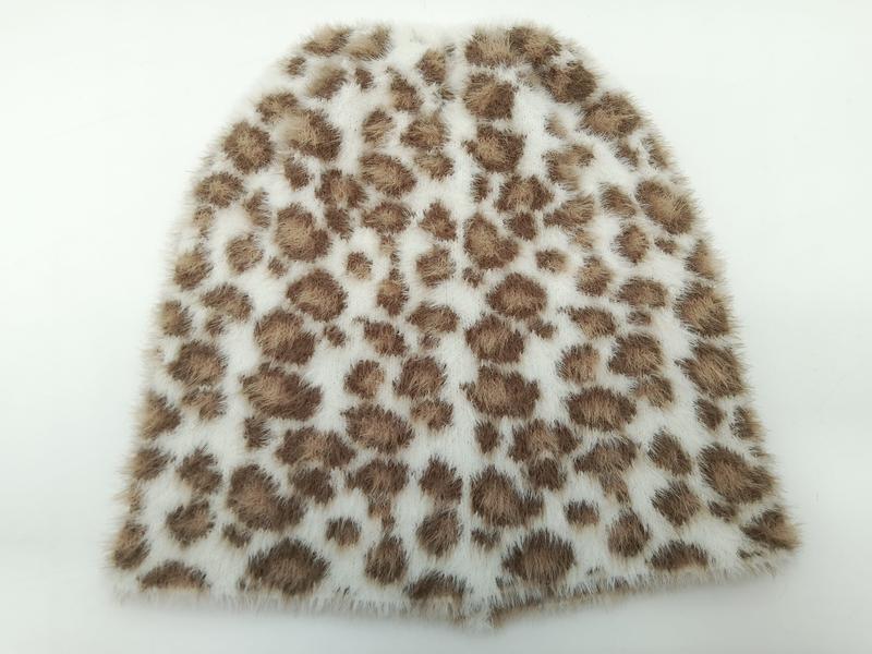 Close-up of soft faux fur fabric swatch with brown leopard spot pattern on cream white background - wholesale price for Europe buyers