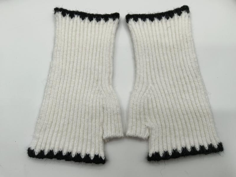 Pair of white ribbed knit fingerless mittens with black zigzag trim at cuff and top, laid flat on white background - bulk order 500+ pcs extra 8% off