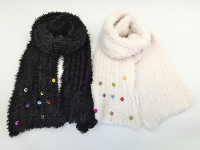 Two fluffy knit scarves in black and cream with multicolor decorative buttons arranged on white background - winter accessories wholesaler
