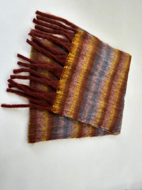 Folded fluffy striped scarf in rust, mustard yellow, and blue tones with long fringe ends on white background - Oeko-Tex Standard 100 certified